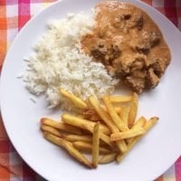 A plate of Brazilian beef stroganoff with fries and rice.