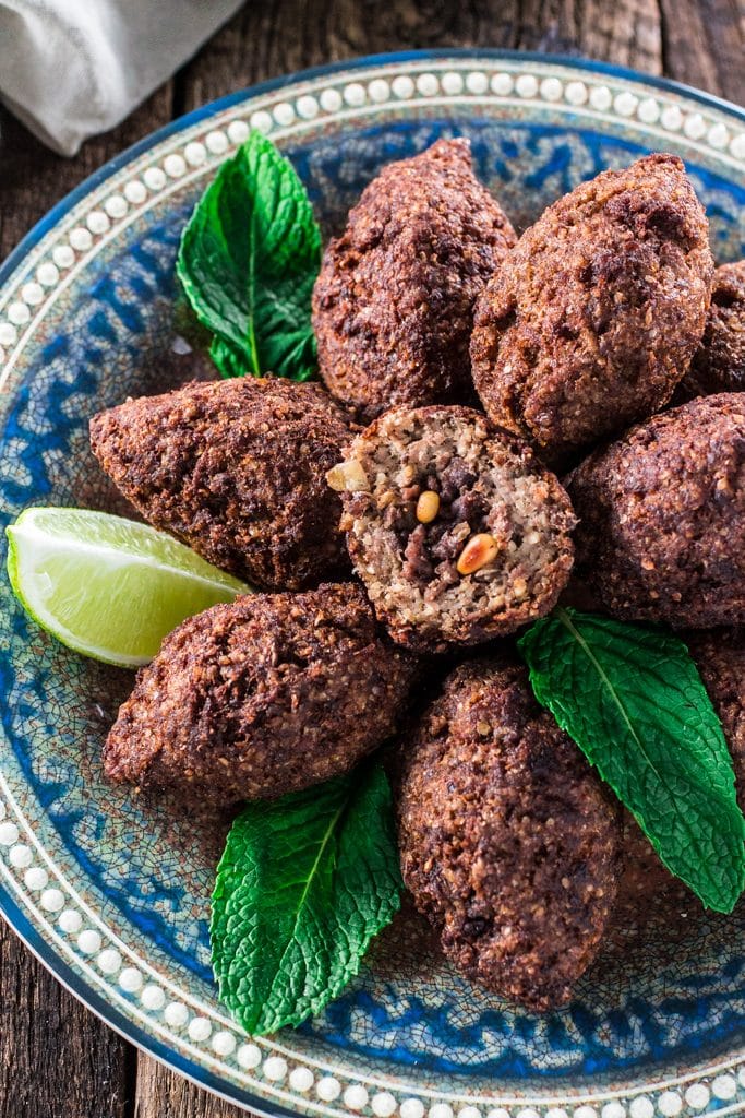 Kibbeh (Lebanese Beef Croquettes) | www.oliviascuisine.com | This Lebanese classic is one of my favorite dishes in the whole world! It consists of a dough made of meat, bulgur (cracked wheat), onions and mint leaves, formed into football shaped croquettes, and filled with more meat, onions, pine nuts and Middle Eastern spices. They are then deep fried to perfection so they are crisp on the outside and soft inside!