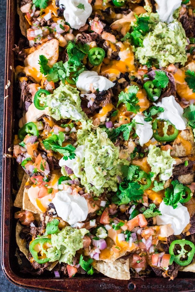 Fully Loaded Nachos | www.oliviascuisine.com | 9 layers of perfection: 3 different kinds of tortilla chips, Chipotle Beer Shredded Beef, Black Beans, the most incredible cheese sauce, more cheese, pico de gallo salsa, jalapeños, guacamole and sour cream or mexican crema! 