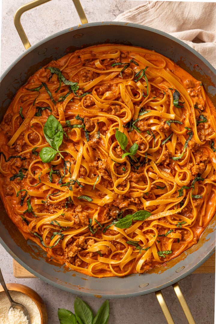 Creamy tomato pasta with spicy sausage and basil in a skillet