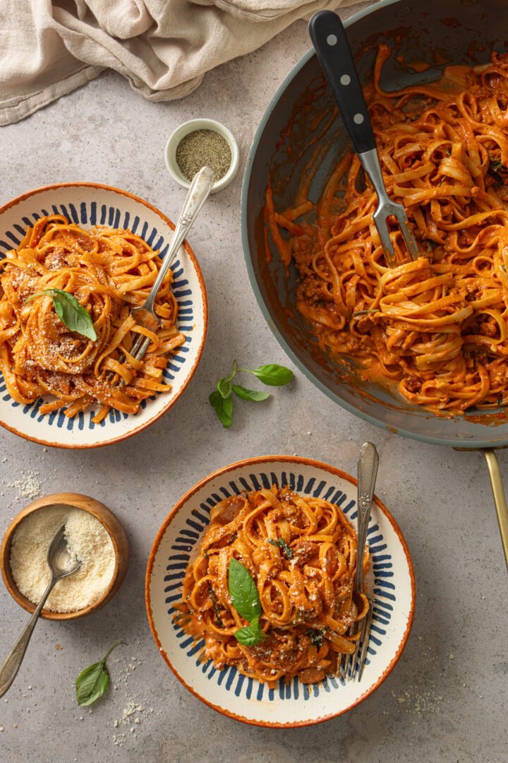 Bowls of creamy one pan pasta with spicy sausage and fresh basil