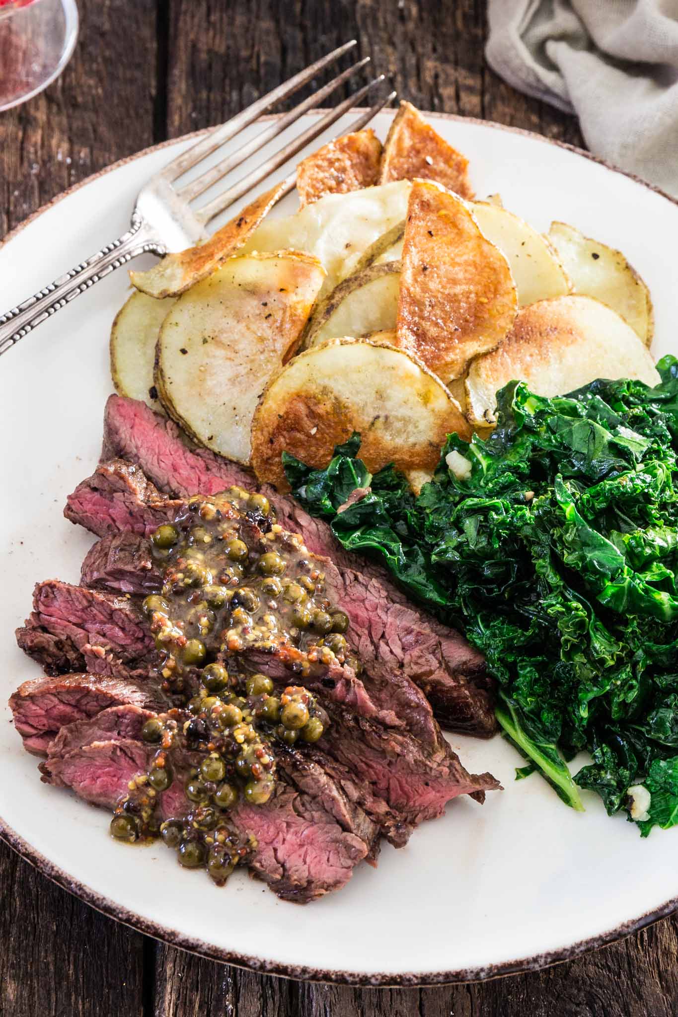 Steaks with Green Peppercorn Sauce | www.oliviascuisine.com | If you're looking for an impressive meal that is easy enough to put together on a weekday, this Steak with Green Peppercorn Sauce is the answer! The steak is cooked to perfection and served with a silky mustard-y peppercorn sauce, kale and roasted potatoes.