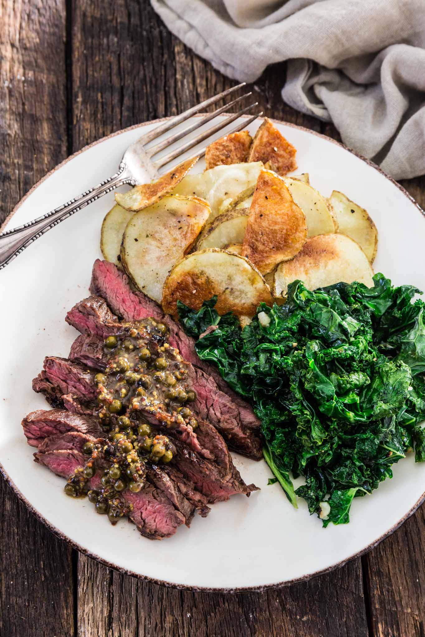 Steaks with Green Peppercorn Sauce | www.oliviascuisine.com | If you're looking for an impressive meal that is easy enough to put together on a weekday, this Steak with Green Peppercorn Sauce is the answer! The steak is cooked to perfection and served with a silky mustard-y peppercorn sauce, kale and roasted potatoes.