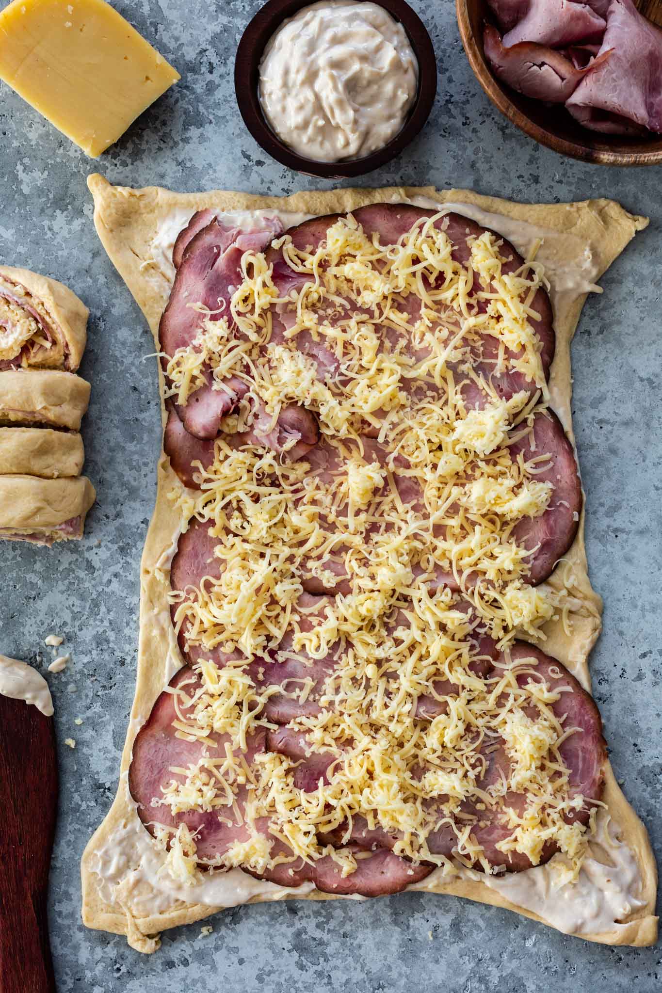 Assembling of ham and cheese pinwheels on a sheet of crescent roll.