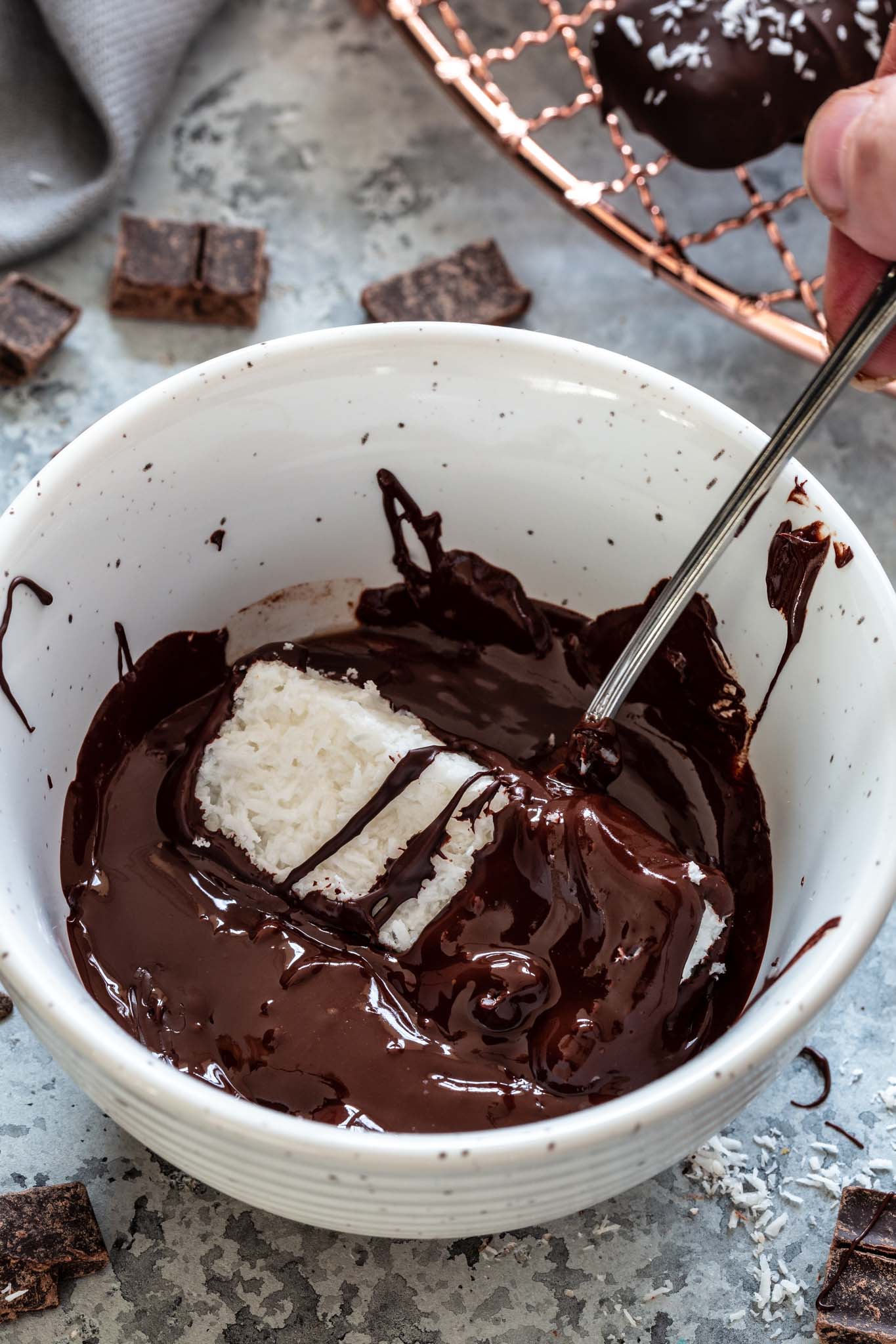 Coconut bar being rolled in melted low carb chocolate