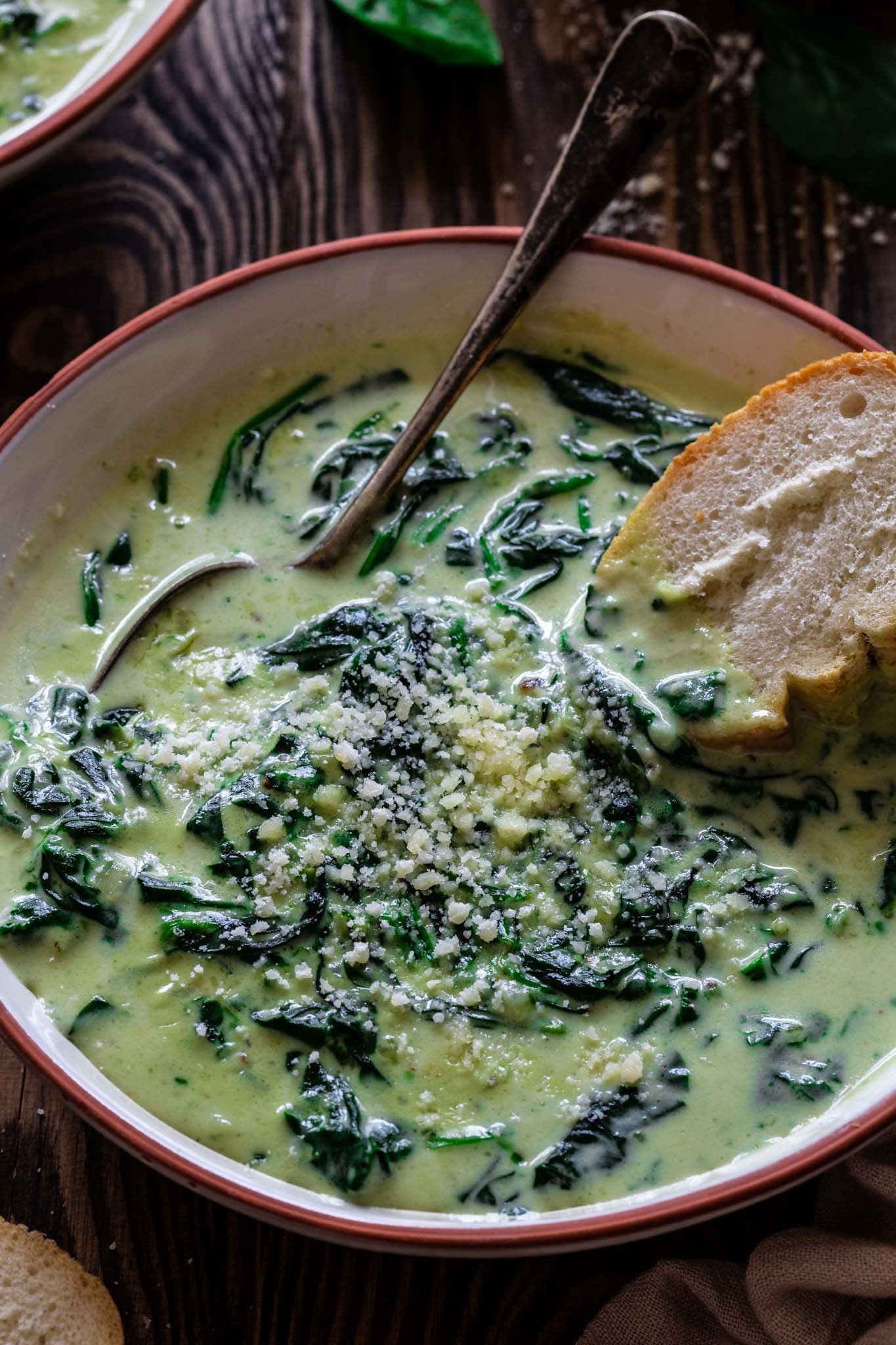 a close up of grated parmesan on creamy spinach soup