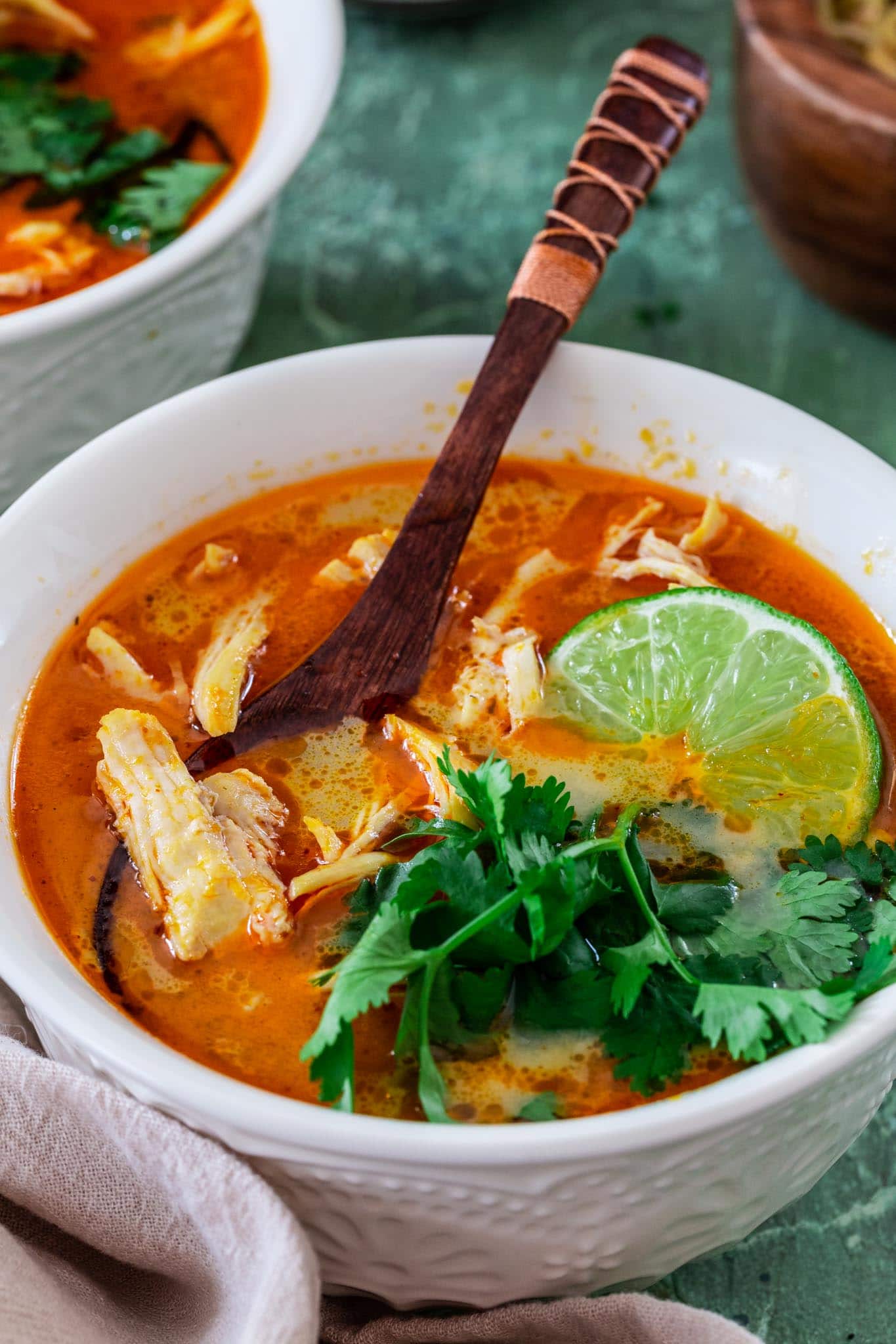 a bowl of Tom Kha Soup, garnished with cilantro and lime