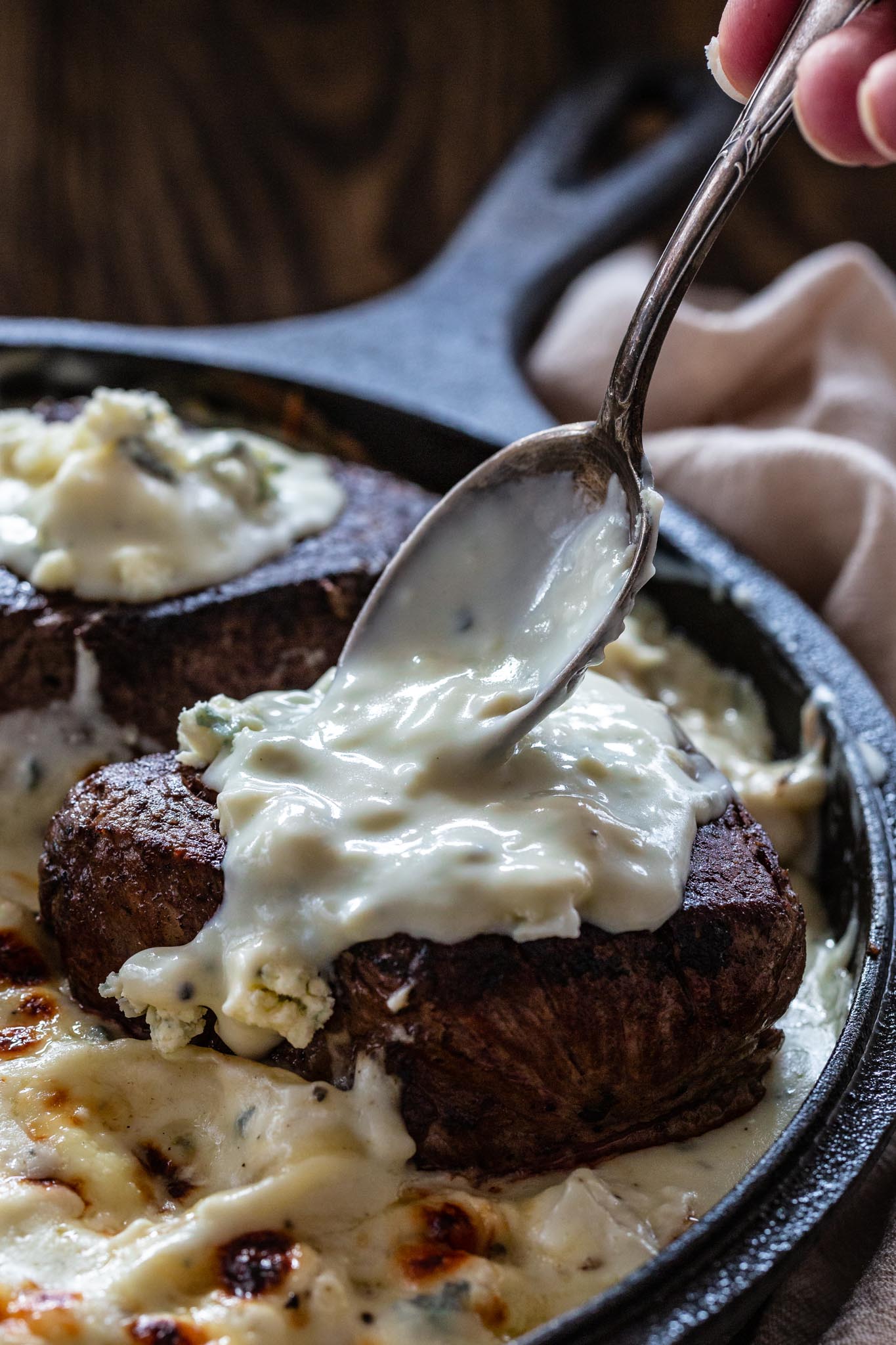 Luscious gorgonzola sauce being spooned on a juicy tenderloin steak.