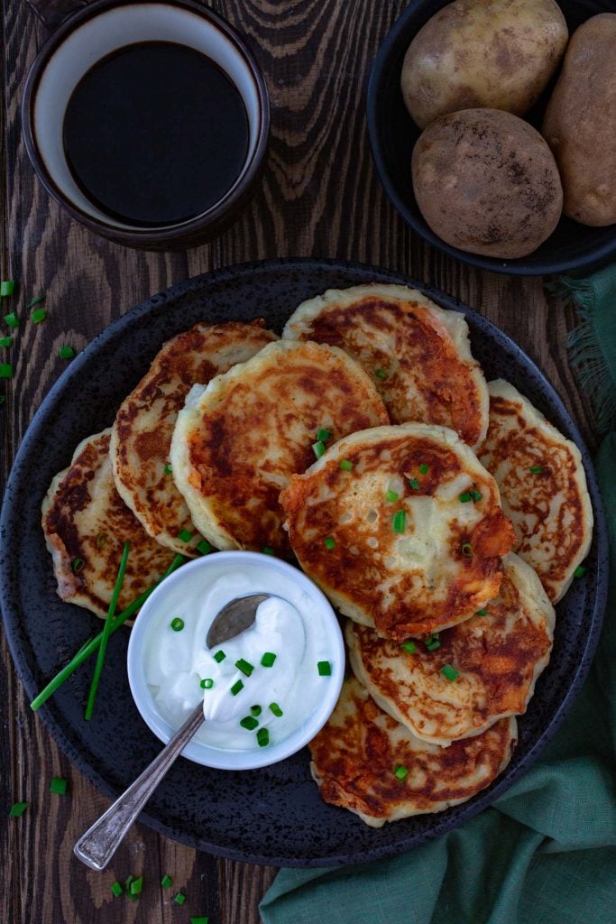 A plate of mashed potato pancakes, served with sour cream.