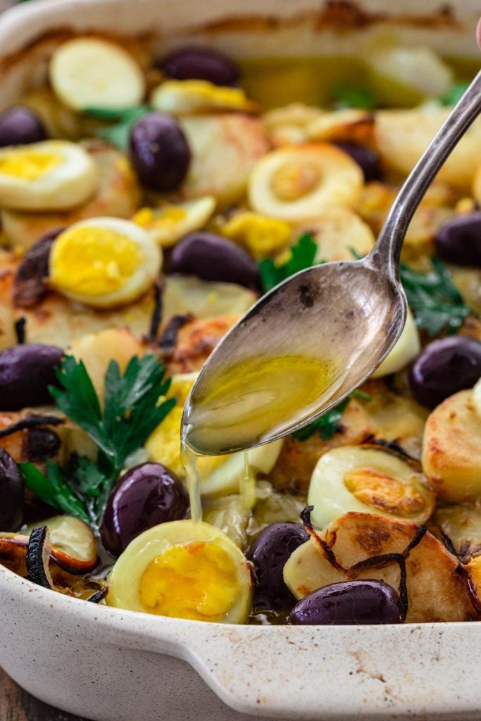 Pouring olive oil over the bacalao.