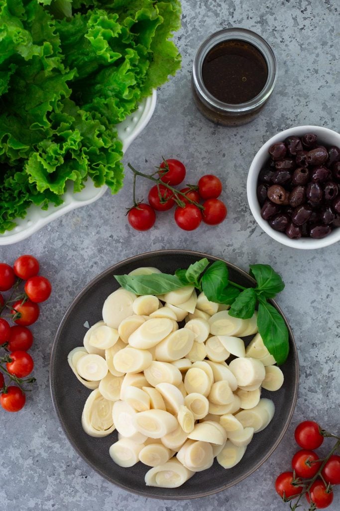 Ingredients for Brazilian salad with hearts of palm, cherry tomatoes, olives, lettuce and basil.