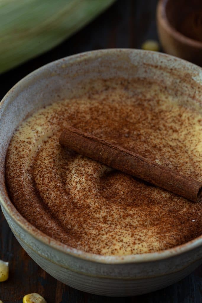 Brazilian corn pudding dusted with cinnamon and garnished with a cinnamon stick