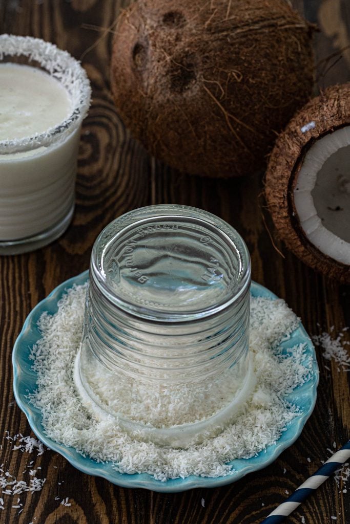 Rimming the serving glass with shredded coconut.