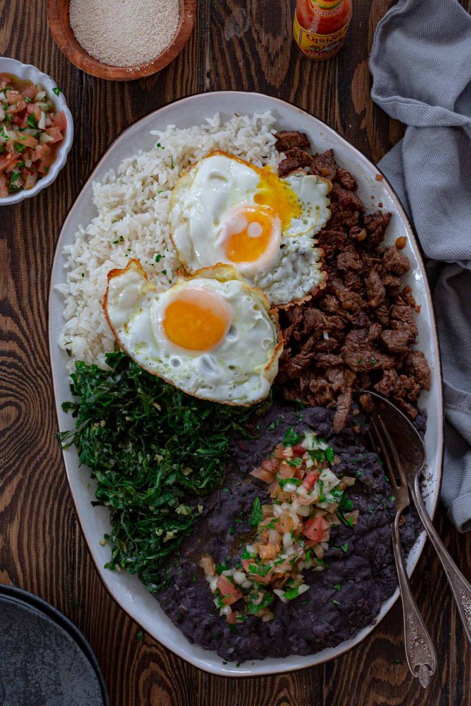 Tutu de Feijão served with rice, beef, collard greens and eggs.