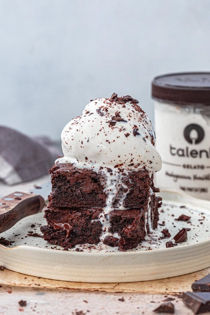 Brownies topped with ice cream and chocolate shavings.