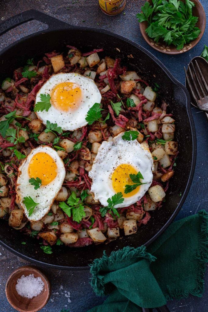 A cast iron skillet with corned beef hash and fried eggs