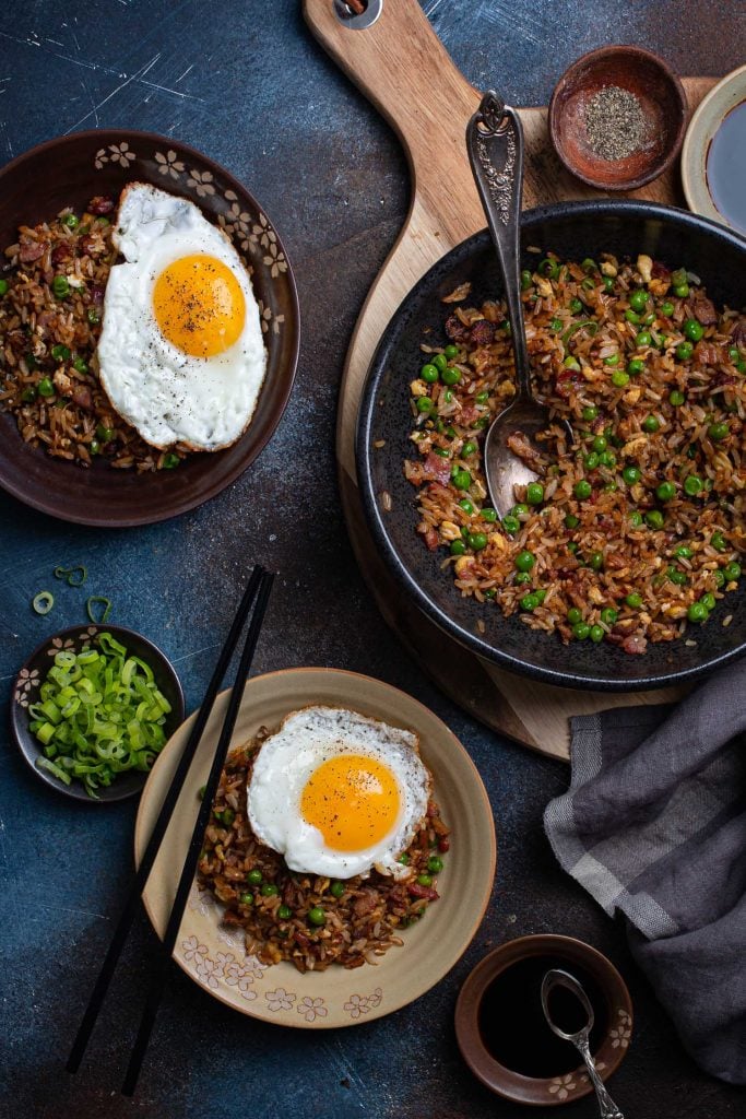 A serving scene. You can see the main bowl and two individual bowls, topped with fried eggs. 