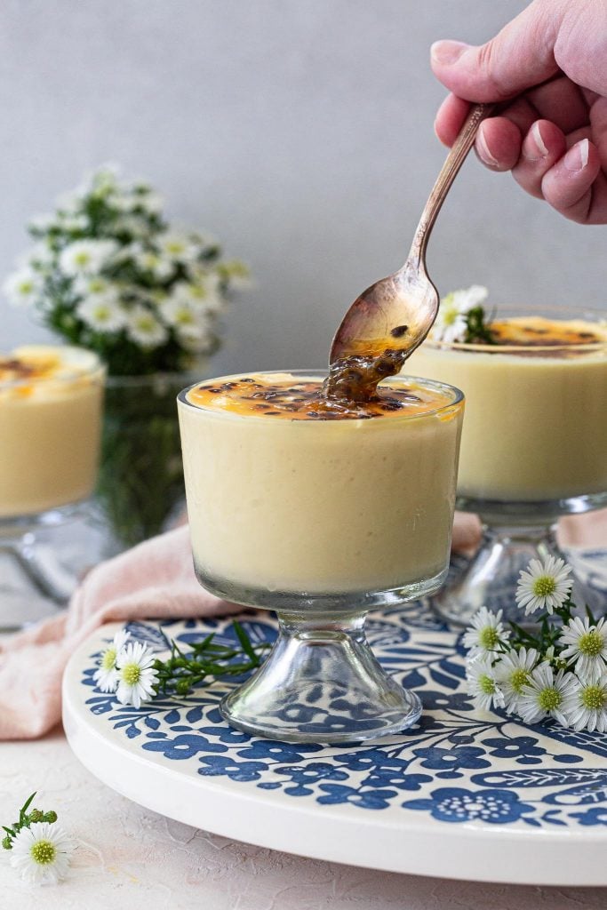 Topping a glass of passion fruit mousse with passion fruit sauce.