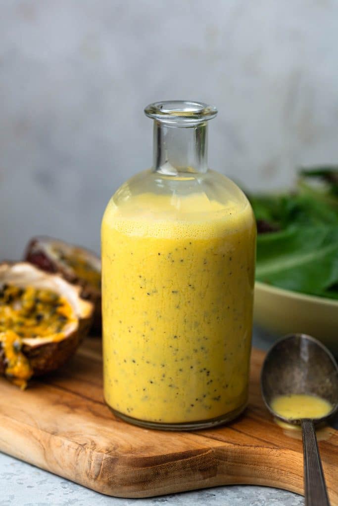 A bottle of passion fruit dressing on a cutting board.
