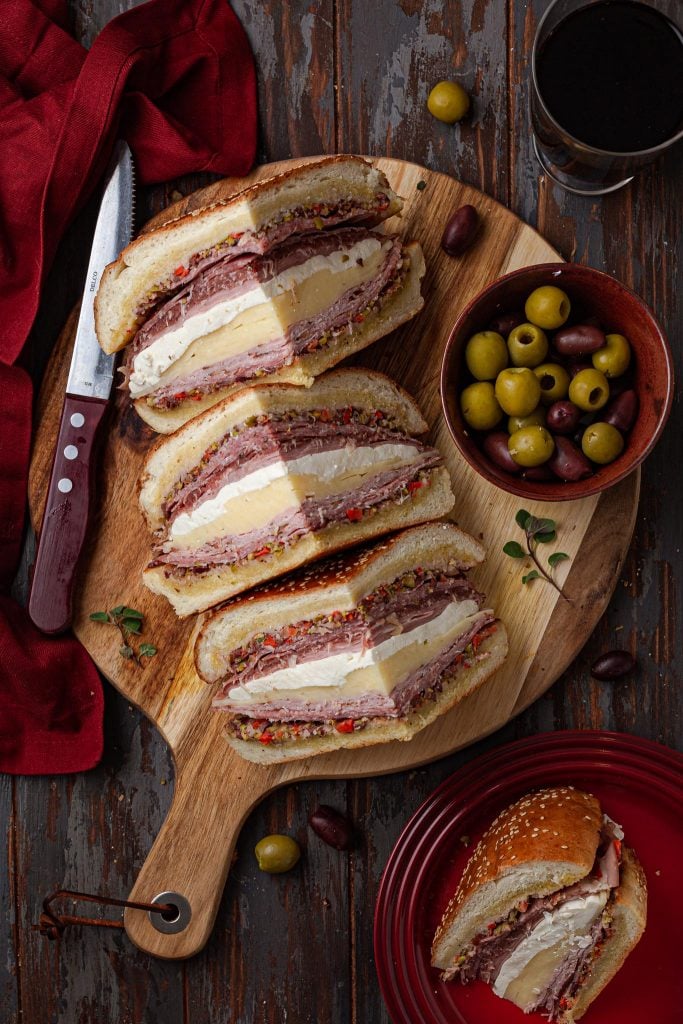 An overhead photo of three Muffulettas on a serving board.