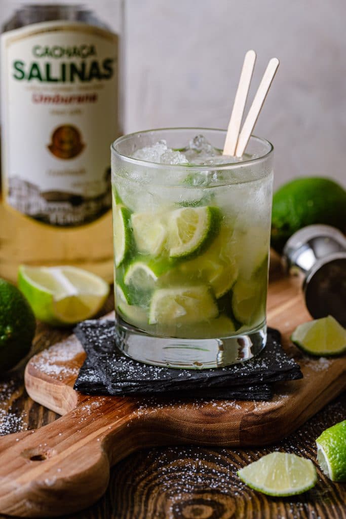 A caipirinha in an Old Fashioned glass, on a cutting board.