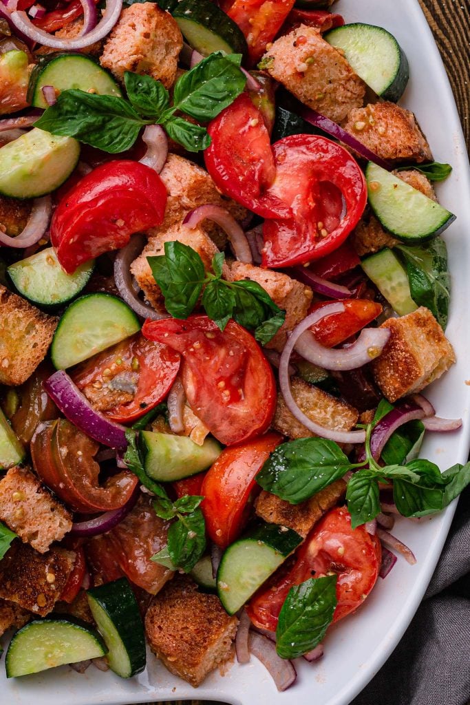 Close up shot of a Tuscan bread and tomato salad, with basil, cucumbers and red onions.