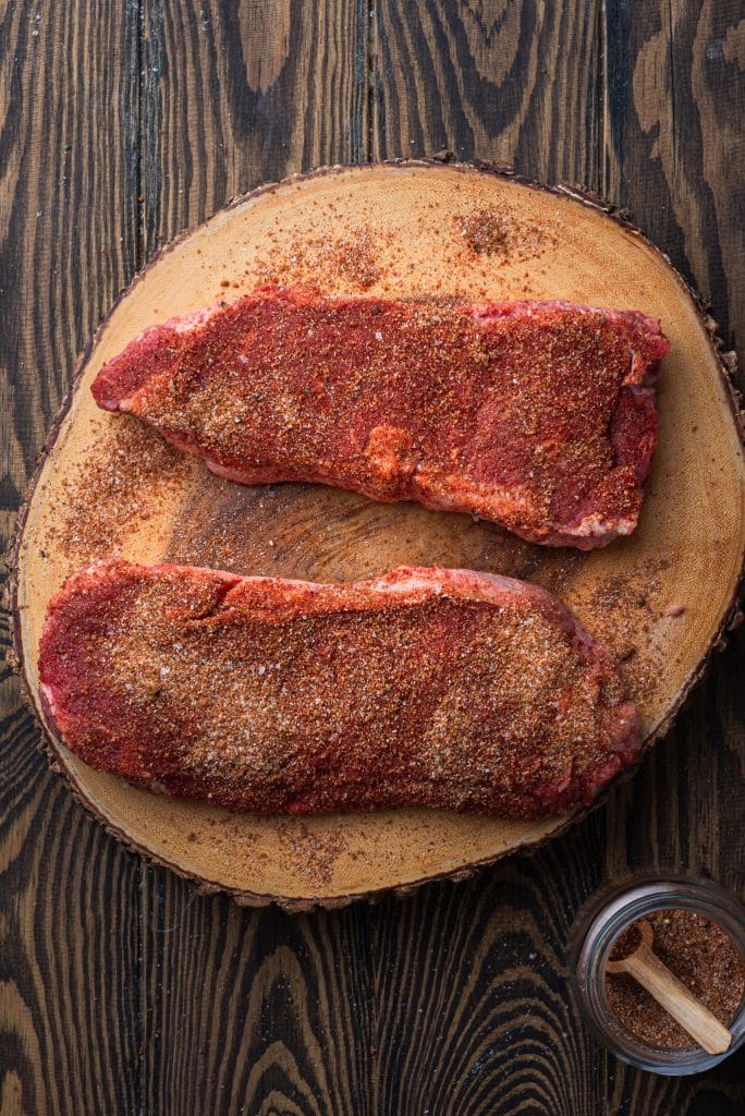 Raw steaks coated with rub.