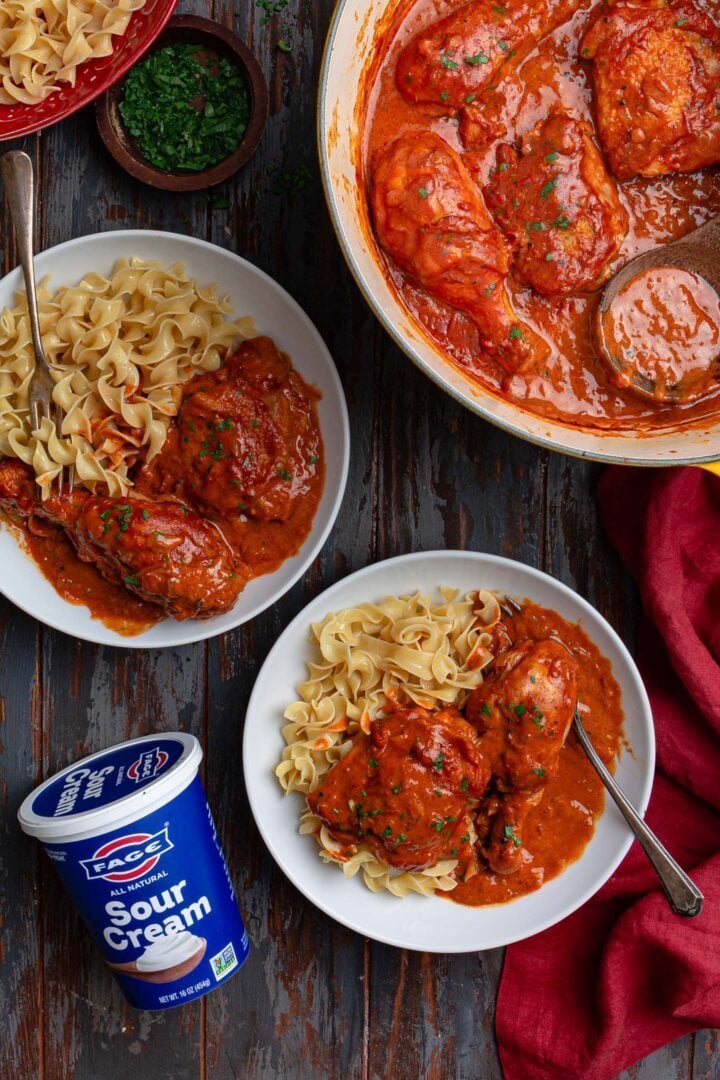 Two bowls with Paprika Chicken and a container of sour cream.