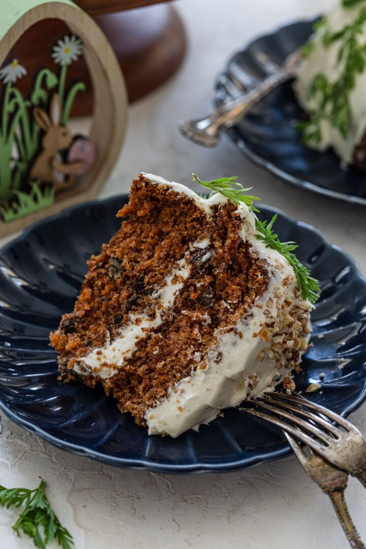 A big slice of carrot cake on a plate with two forks.