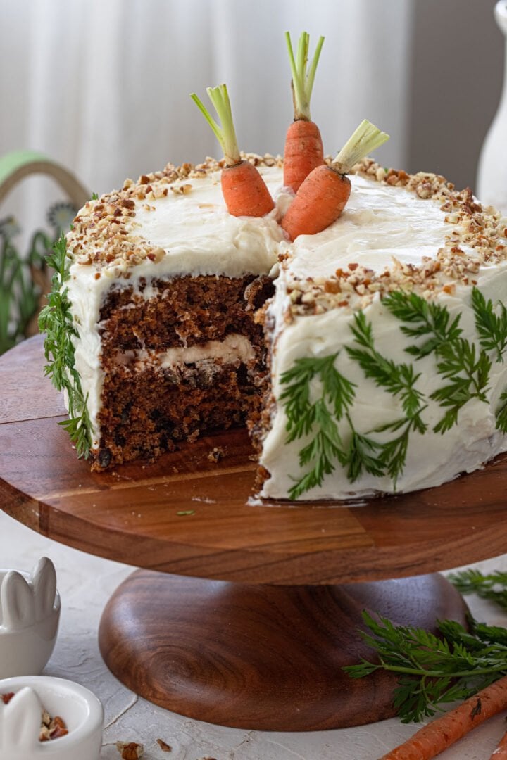 A cut carrot cake on a cake stand.