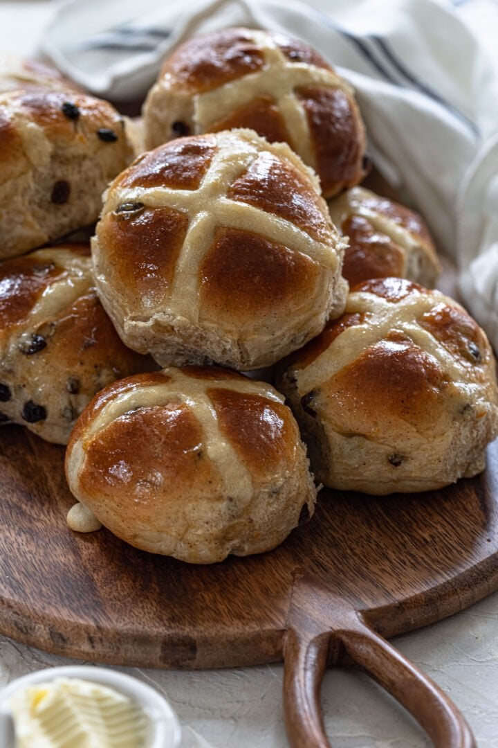 A batch of hot cross buns on a wood board.