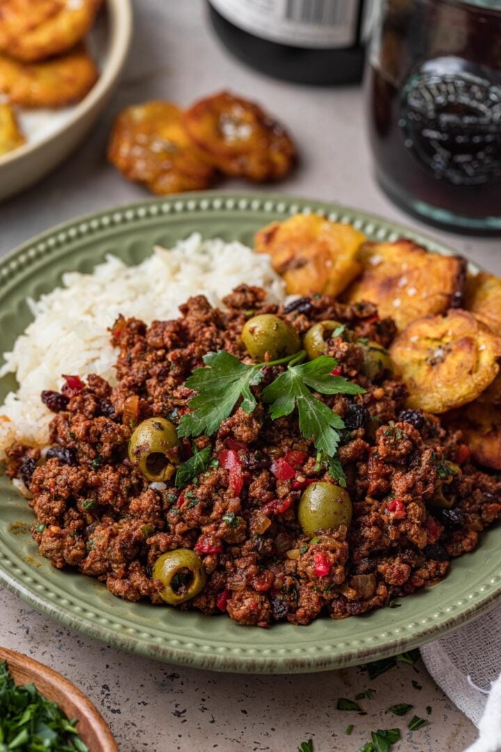 A plate of beef picadillo with rice and tostones.