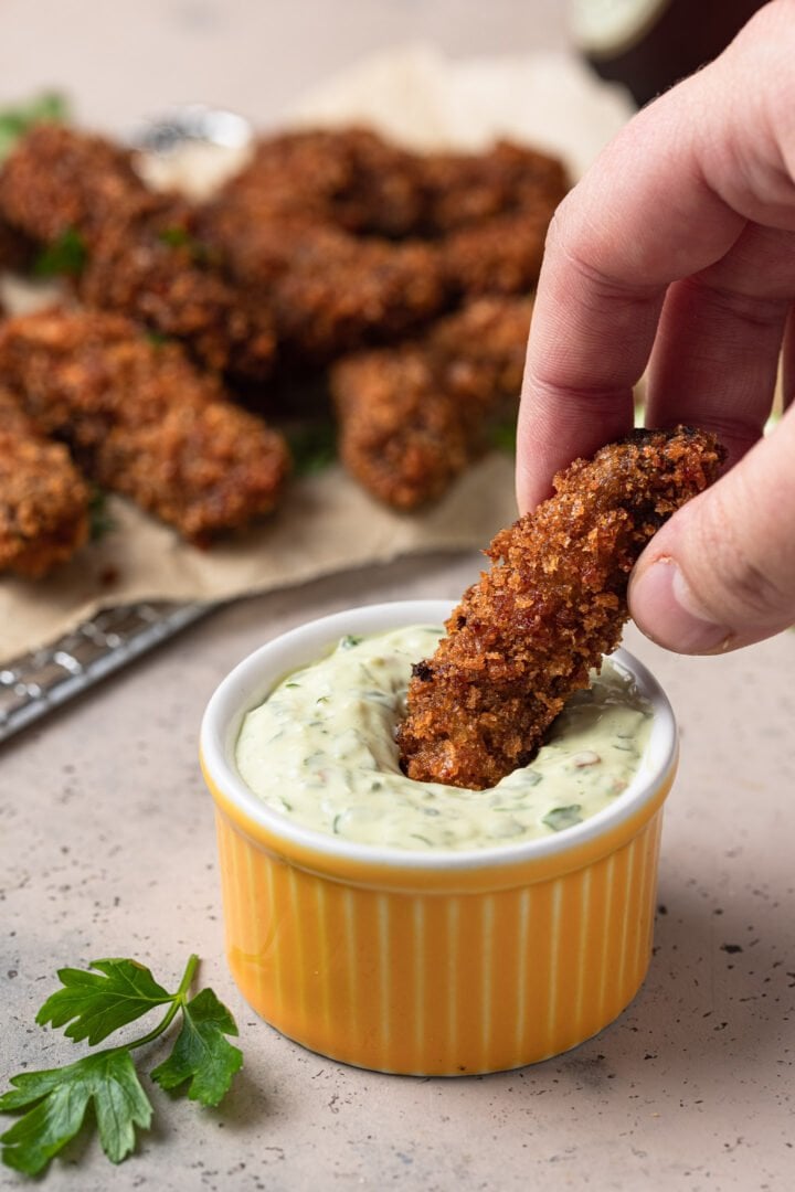 A hand dipping a finger steak on chimichurri mayo.