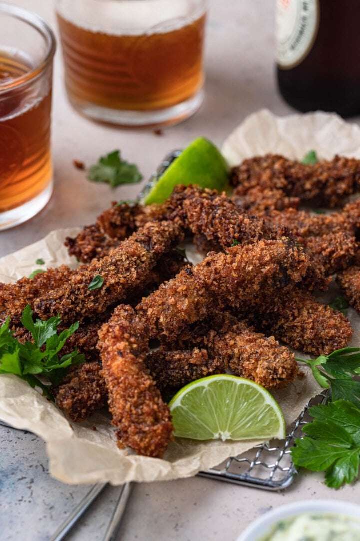 Crispy finger steaks served with beer and lime wedges.