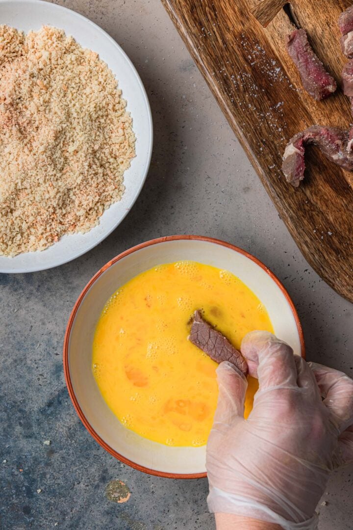 Dipping the steak in egg.