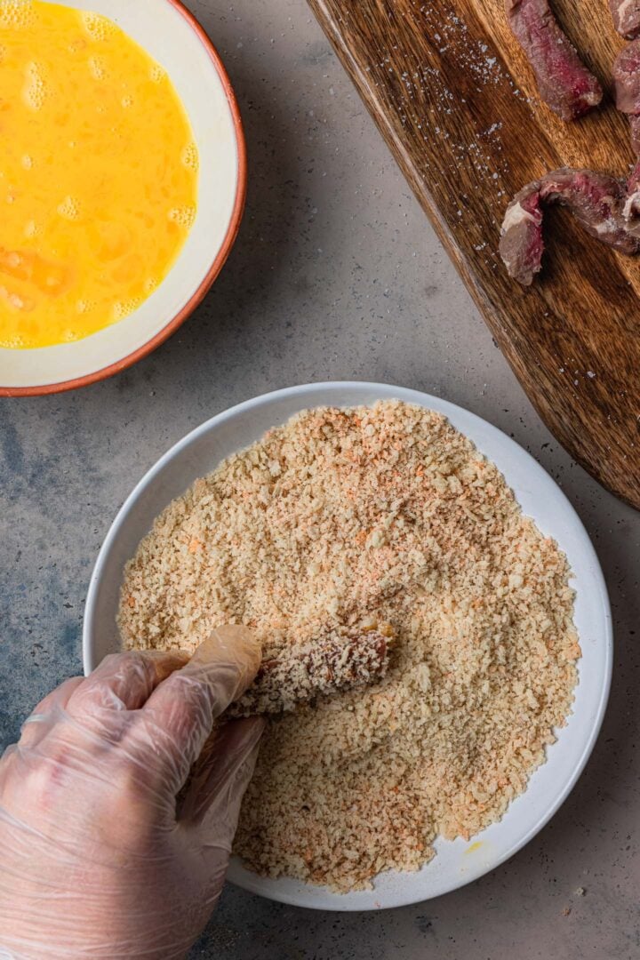 Coating the steak with the breadcrumbs.