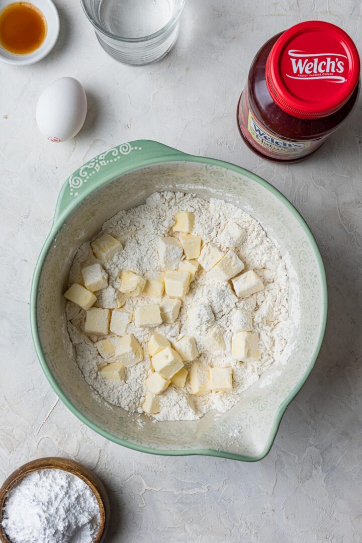 A bowl with butter scattered on flour, to make pie dough.