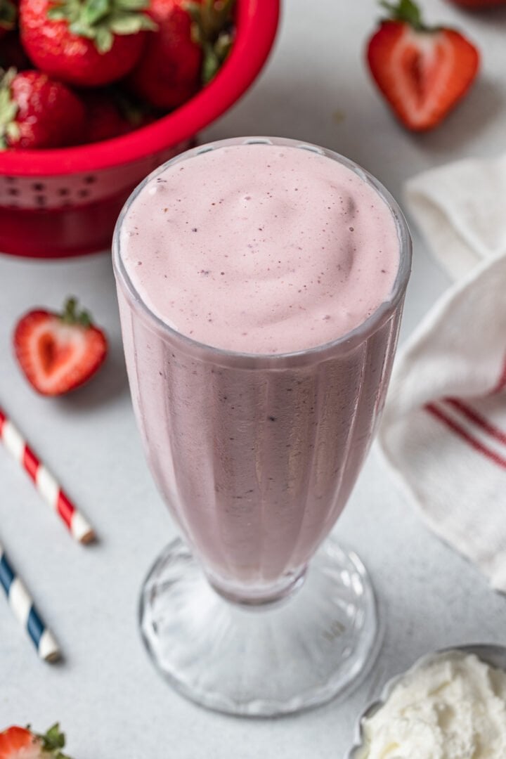 A glass of strawberry milkshake without toppings.