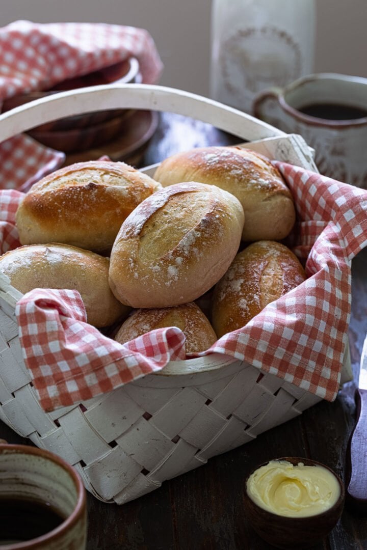 A basket of pão francês served with butter and coffee.