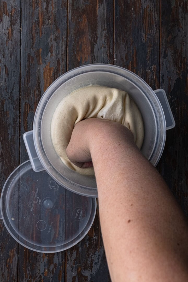 Punching down the dough to deflate it.