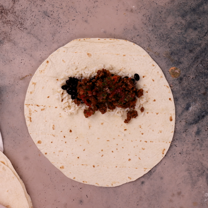 Assembling the beef burrito. Fourth layer: salsa.