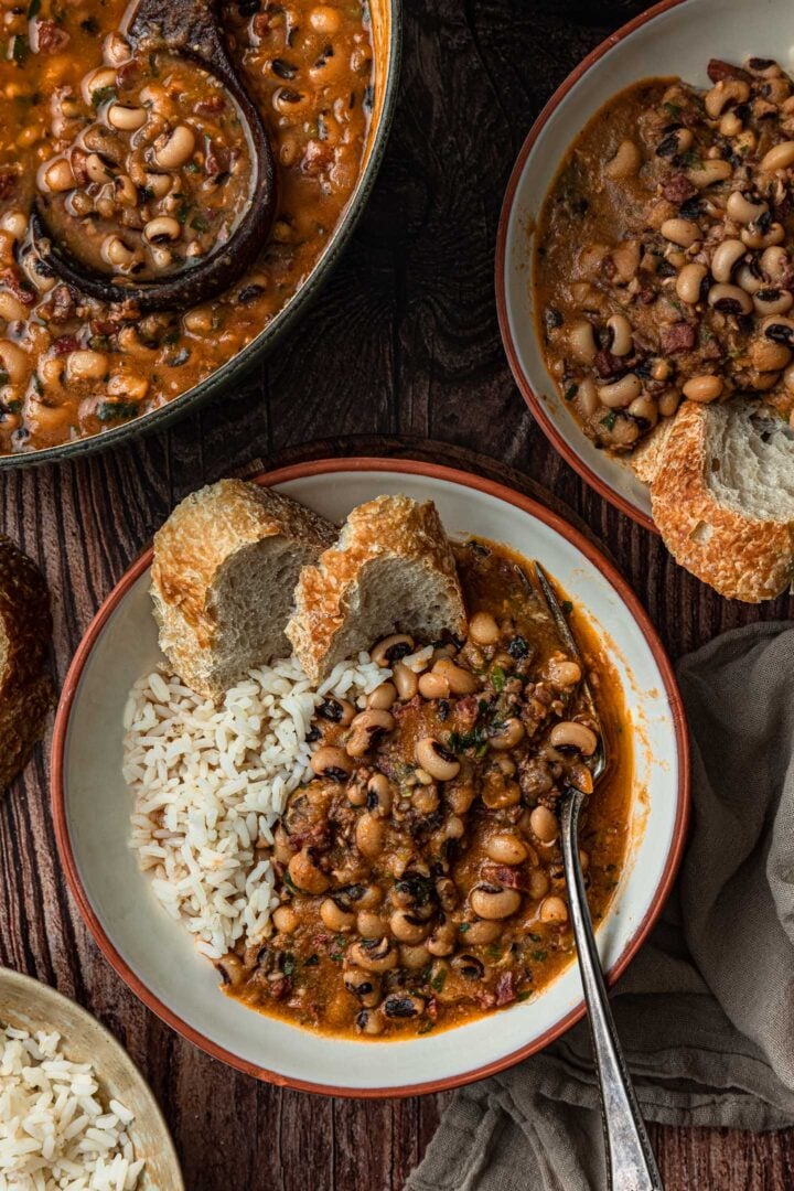 A serving of black-eyed peas with white rice and bread in a bowl.