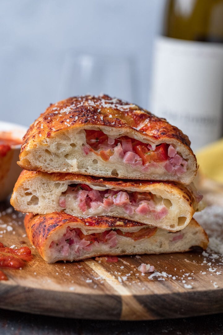 Three calzone halves. You can see the melty cheese, ham and tomatoes inside.