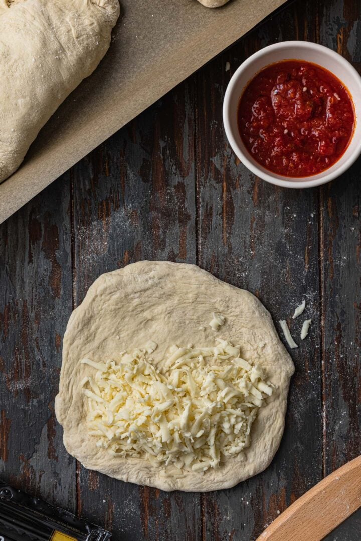 Layering the calzone: Cheese on pizza dough.