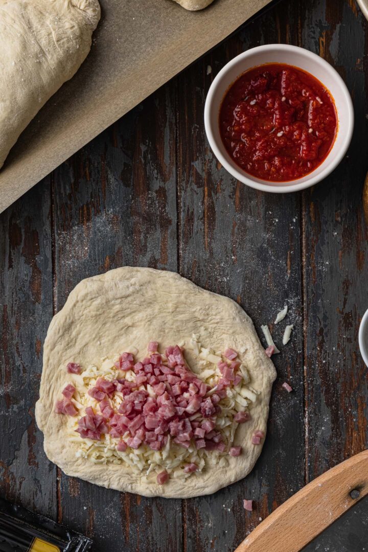Layering the calzone: Ham over the cheese.