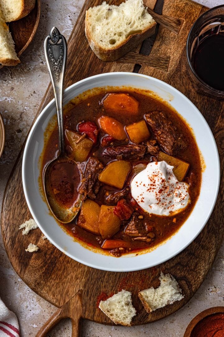 A bowl of goulash soup, topped with a dollop of sour cream.