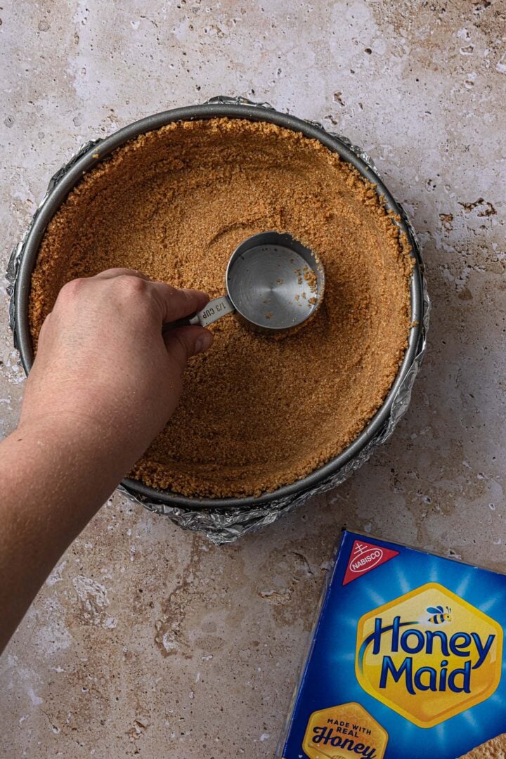 Pressing the crumbs into the springform pan.