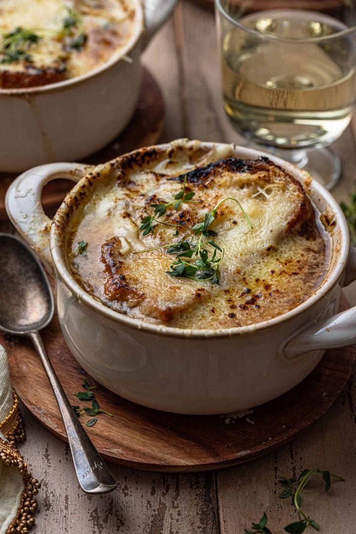 A bowl of French onion soup, garnished thyme.