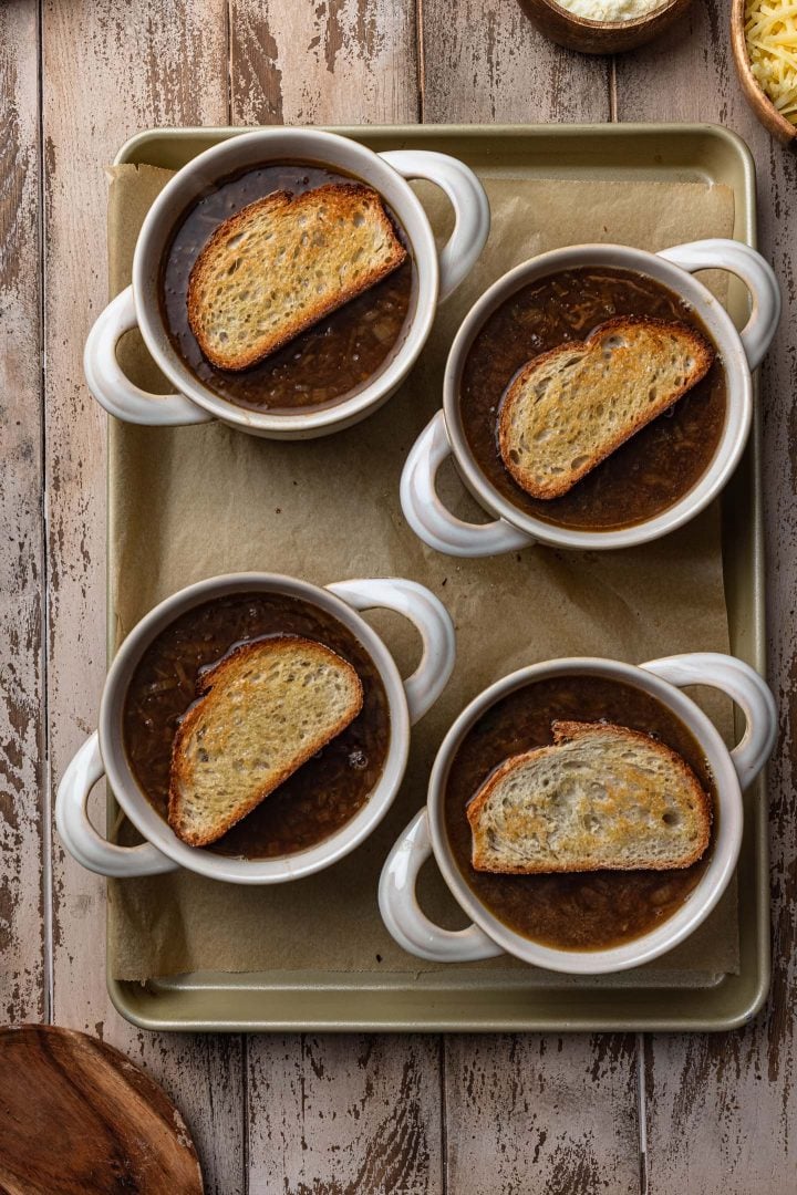 Four onion soup bowls, topped with the bread.