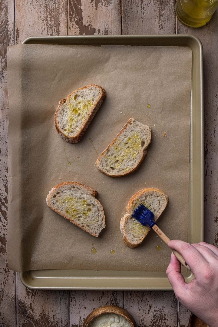 Brushing the bread slices with olive oil.